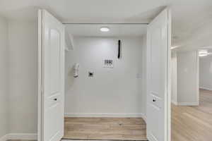 Laundry room with hookup for an electric dryer, light hardwood / wood-style flooring, and washer hookup