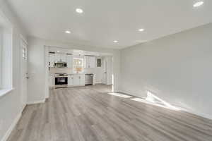 Unfurnished living room with sink, a healthy amount of sunlight, and light hardwood / wood-style flooring