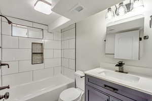 Full bathroom with vanity, toilet, and tiled shower / bath combo