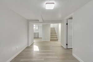 Hall featuring a textured ceiling and light hardwood / wood-style flooring