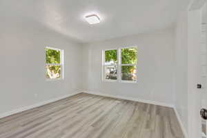 Spare room featuring light hardwood / wood-style floors and plenty of natural light