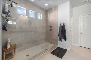 Bathroom with tile patterned flooring and a tile shower