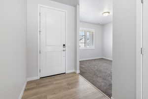 Foyer with light wood finished floors and baseboards