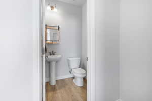 Half bathroom with a sink, wood finished floors, toilet, and baseboards