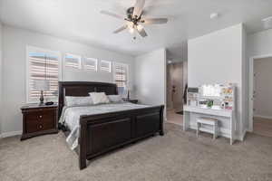 Bedroom featuring ensuite bathroom, ceiling fan, and light colored carpet