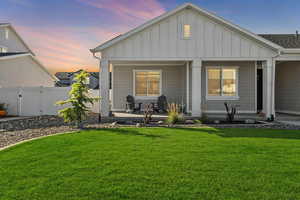 Back house at dusk featuring a yard