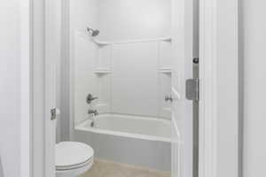 Bathroom featuring bathtub / shower combination, tile patterned flooring, and toilet