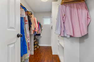 Walk in closet with dark wood-type flooring