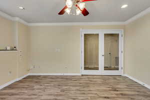 Double french door office or exercise room featuring french doors, laminate type flooring, ceiling fan, and crown molding