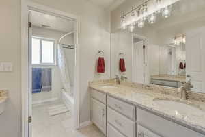 Bathroom with shower / bath combo, double granite counter top vanity, and tile patterned flooring