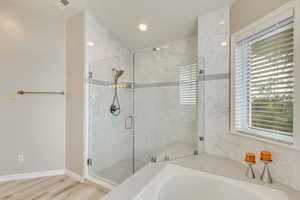 Upgraded master bathroom featuring plenty of natural light, LVP flooring, and independent shower and bath