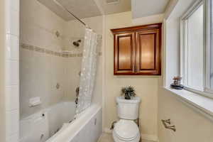 Basement Bathroom featuring shower / jetted tub combo, tile patterned flooring, extra cabinet