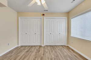 Large size bedroom featuring lamiate floors, double closets, and ceiling fan