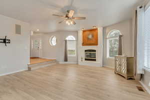 Large family room featuring a fireplace, ceiling fan, and LVP style flooring