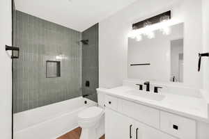 Full bathroom with toilet, vanity, tiled shower / bath, and wood-type flooring