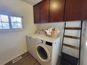 Laundry area featuring washer and clothes dryer, dark wood-type flooring, and cabinets