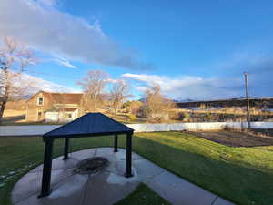 Outdoor fire pit, a yard, a gazebo, and a patio area