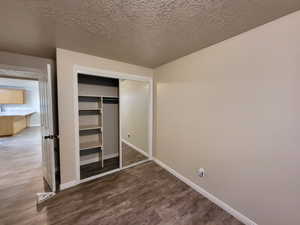 Bedroom featuring dark hardwood / wood-style floors, a textured ceiling, and a closet