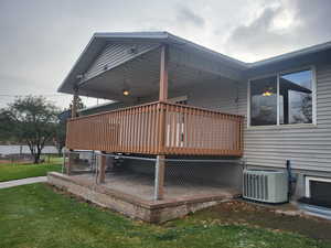 View of home's exterior featuring central AC, a lawn, and a wooden deck