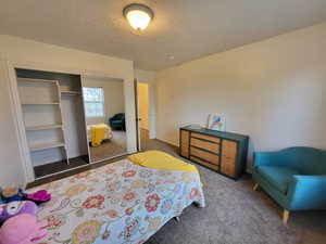 Carpeted bedroom featuring a textured ceiling and a closet