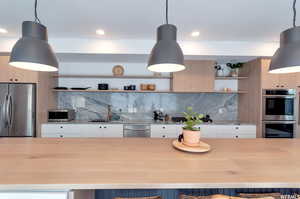 Kitchen with pendant lighting, stainless steel appliances, and white cabinets