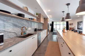 Kitchen featuring sink, white cabinetry, pendant lighting, and decorative backsplash