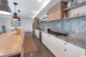 Kitchen with white cabinets, sink, tasteful backsplash, appliances with stainless steel finishes, and decorative light fixtures