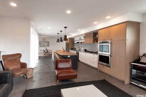 Kitchen featuring beverage cooler, a kitchen island, backsplash, appliances with stainless steel finishes, and decorative light fixtures