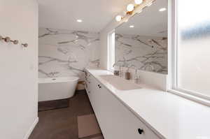 Bathroom featuring tile walls, a washtub, and vanity