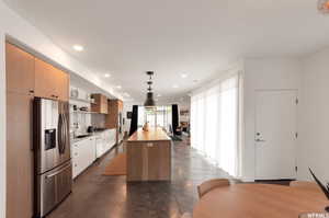 Kitchen featuring concrete floors, sink, a center island, stainless steel fridge, and decorative backsplash