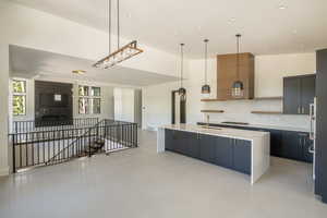 Kitchen with tasteful backsplash, a kitchen island with sink, sink, and pendant lighting