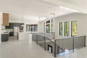 Hallway with lofted ceiling with beams, an inviting chandelier, and a wealth of natural light