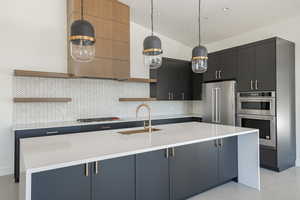 Kitchen featuring a center island with sink, sink, hanging light fixtures, and stainless steel appliances