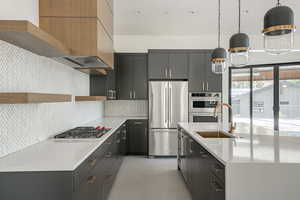 Kitchen featuring tasteful backsplash, sink, hanging light fixtures, and appliances with stainless steel finishes