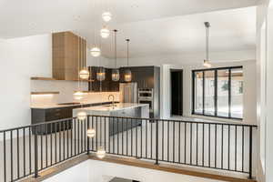 Kitchen featuring sink, hanging light fixtures, stainless steel appliances, tasteful backsplash, and a center island with sink