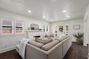 Living room featuring a textured ceiling, dark hardwood floors, and a fireplace