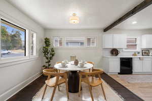 Dining room featuring a textured ceiling, dark hardwood / wood-style floors, and beam ceiling