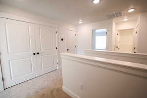 Hallway featuring light colored carpet