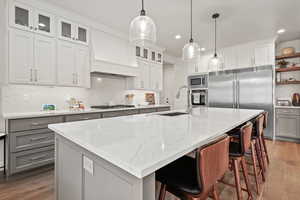 Kitchen featuring built in appliances, a center island with sink, pendant lighting, and sink