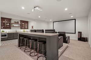 Home theater room with light colored carpet and wet bar