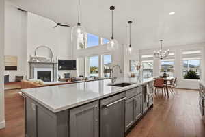 Kitchen featuring gray cabinetry, sink, pendant lighting, an island with sink, and dark hardwood / wood-style flooring