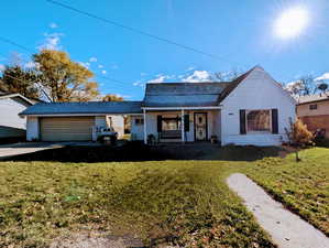 View of front facade with a garage, a front lawn, and a porch