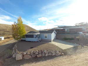 View of front of home with a mountain view, a sunroom, and a patio area