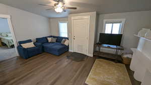 Living room with a wealth of natural light, ceiling fan, and dark hardwood / wood-style flooring