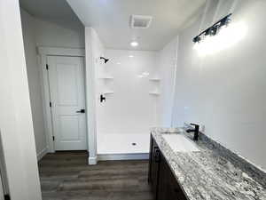 Bathroom with walk in shower, wood-type flooring, and vanity