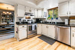 Kitchen with white cabinetry, appliances with stainless steel finishes, and light hardwood / wood-style floors