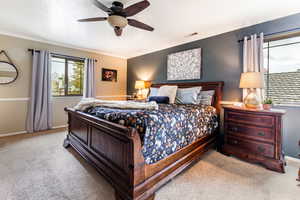 Carpeted bedroom featuring ornamental molding and ceiling fan