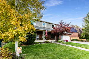 View of front of home featuring a garage, a porch, and a front yard