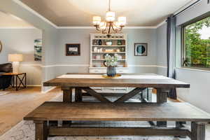 Carpeted dining room with a notable chandelier and ornamental molding