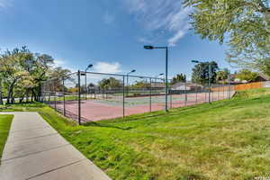 View of tennis court featuring a yard